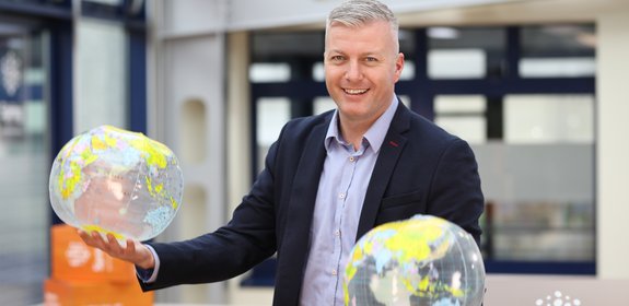 Spring GDS representative holding two globes symbolising global e-commerce delivery.