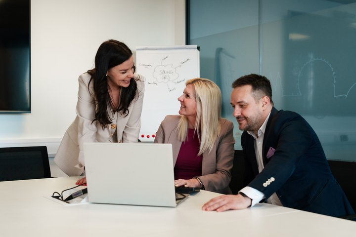 three office workers discussing over a laptop