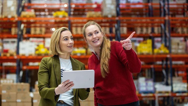 Zwei Mitarbeiterinnen inspizieren Pakete in einem Fulfillment-Center.