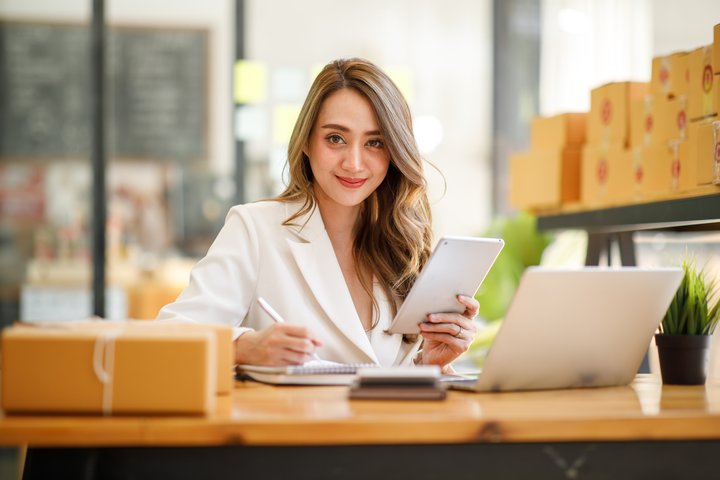 Smiling woman sitting in front of a laptop and parcels.