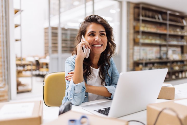 lady smiling on the phone in front of a laptop in a store
