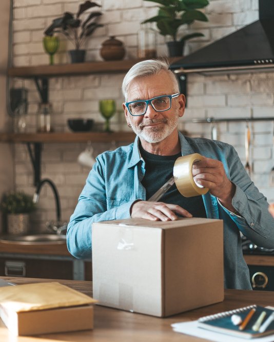 Old man taping a parcel