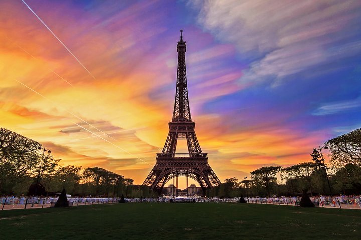 De Eiffeltoren in Parijs afgetekend tegen een levendige zonsondergang, met strepen van roze, oranje en paarse wolken.