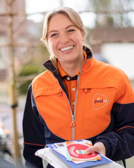 Smiling PostNL delivery worker holding mail and parcels