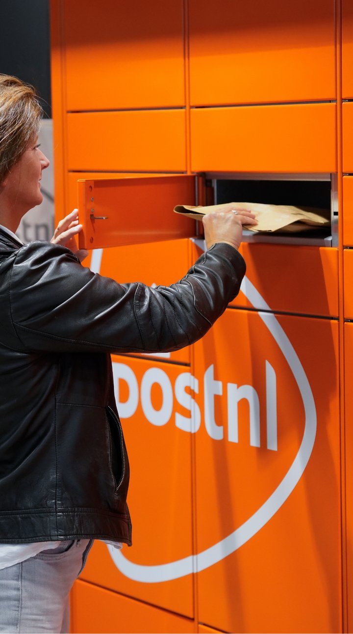 A customer collecting a parcel from a bright orange smart locker, demonstrating flexible e-commerce delivery and return options (PUDO points).