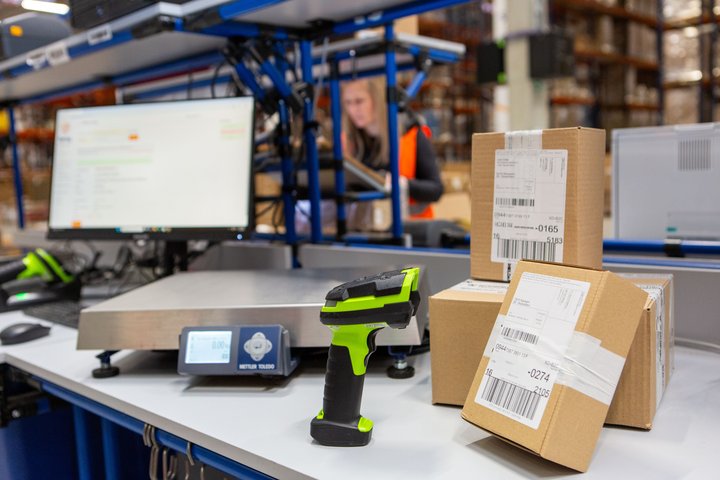 Barcode scanner and labelled parcels on a sorting station in a warehouse.