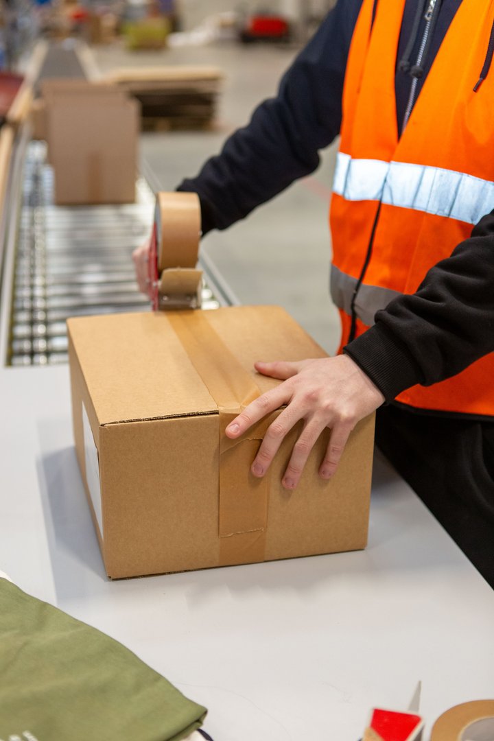 Worker sealing a cardboard parcel with paper tape