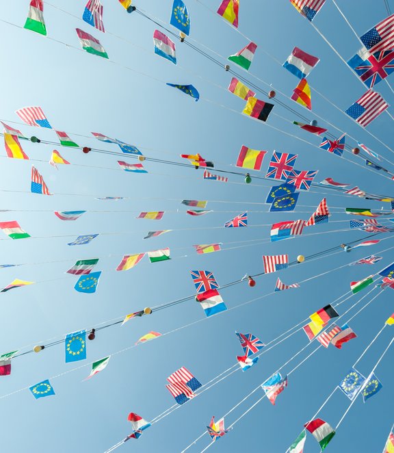 A vibrant display of international flags strung across the sky on a sunny day, symbolizing global unity and celebration.