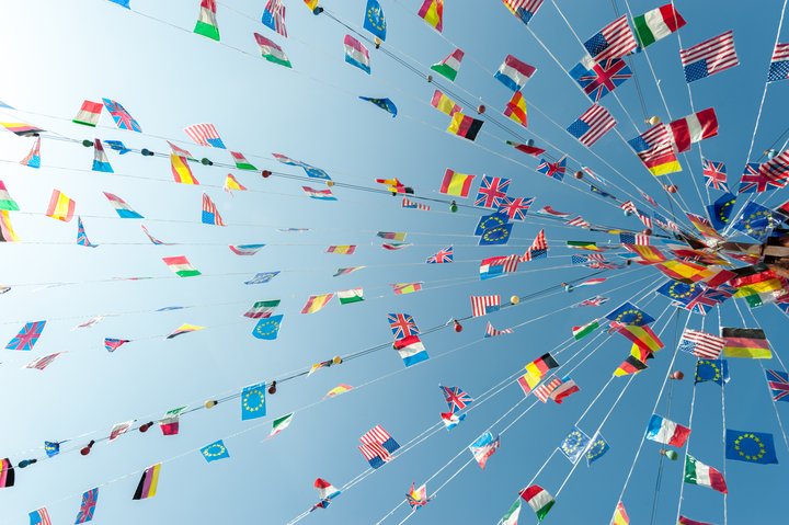 A vibrant display of international flags strung across the sky on a sunny day, symbolizing global unity and celebration.