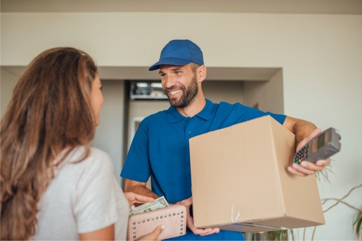 Kobieta płaci za przesyłkę przy odbiorze.