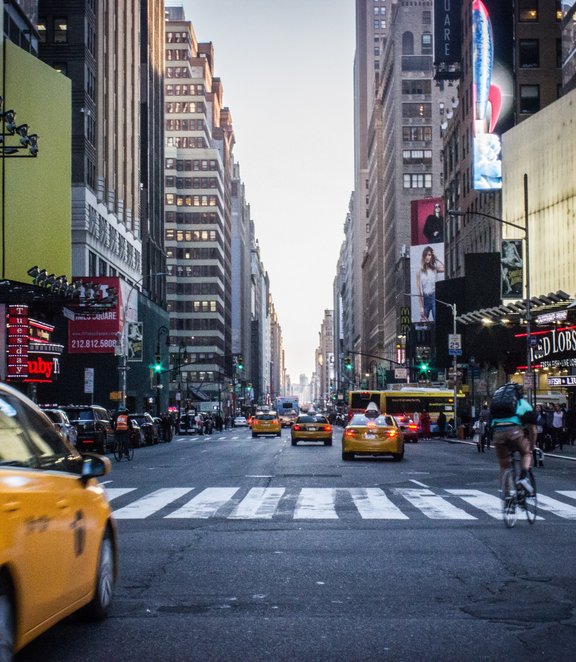 Yellow taxi driving through busy street in new york