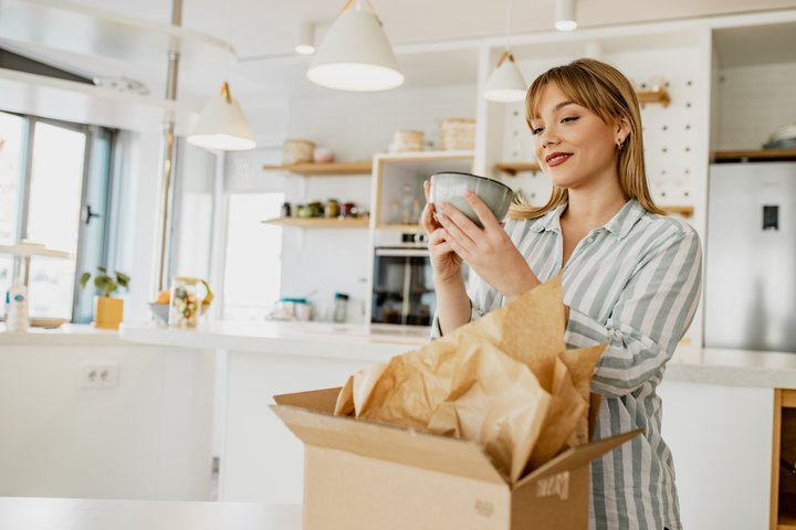 Woman opening a parcel in her kitchen